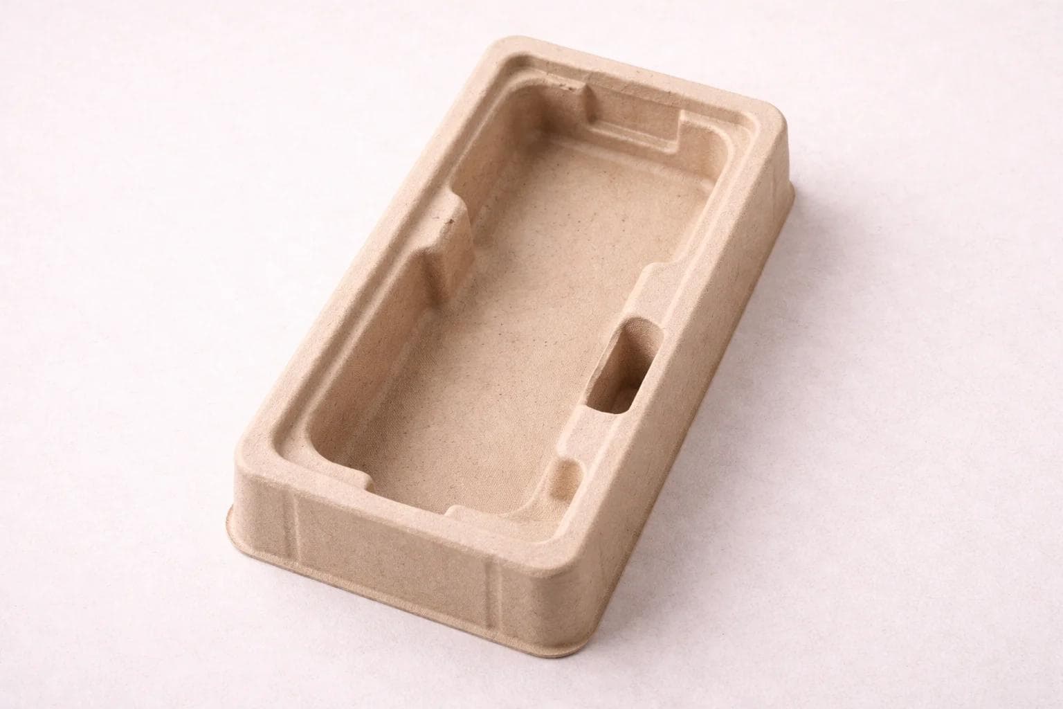 Molded pulp fitment tray shaped around a product outline on a neutral background